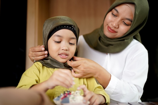 Madre musulmana enseñando a su hija a usar un Hijab.