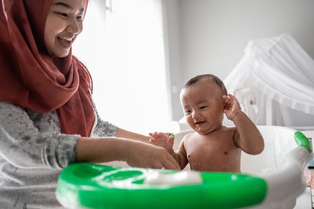 Madre musulmana lavando a niño en la bañera