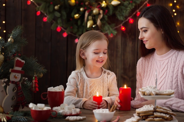 Madre y niña con galletas de Navidad en casa