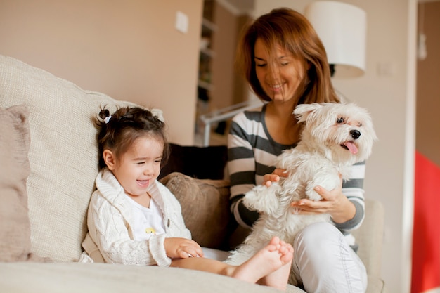 Madre y niña con perro en la habitación.