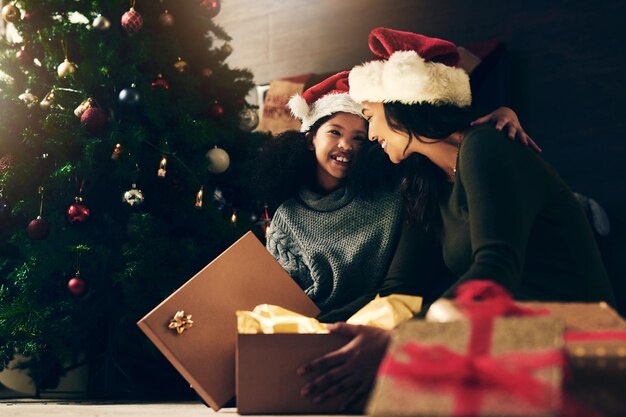 Madre niña y regalo de Navidad celebración navideña y feliz sorpresa árbol decoración y sonrisa en casa Mujer niño y felicidad con caja celebrar o sorprender juntos presentes en casa familiar