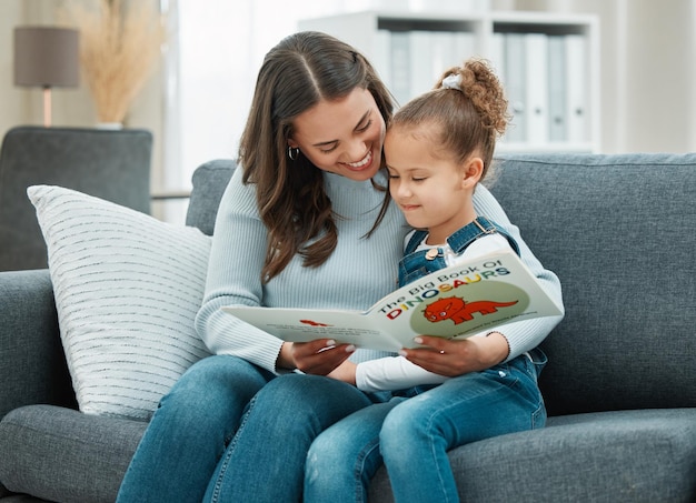 Madre niña y sonrisa con la narración de historias en el sofá en casa para la diversión unión y cuidado con la educación Padre hija y niño con el aprendizaje en la lectura de libros para el conocimiento fantasía y desarrollo del niño