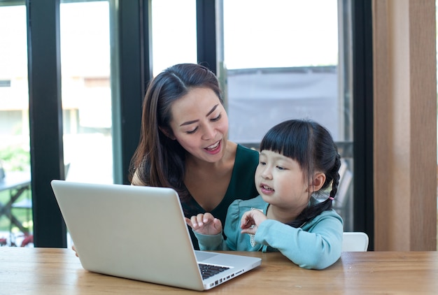 Una madre y una niña usan la computadora en casa