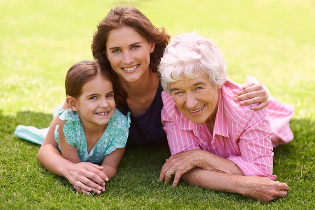 La madre del niño y la abuela se abrazan en el retrato al aire libre para relajarse en las vacaciones de verano o vacaciones juntos La familia feliz y la madre anciana sonríen en la hierba en el jardín con amor y apoyo en la jubilación