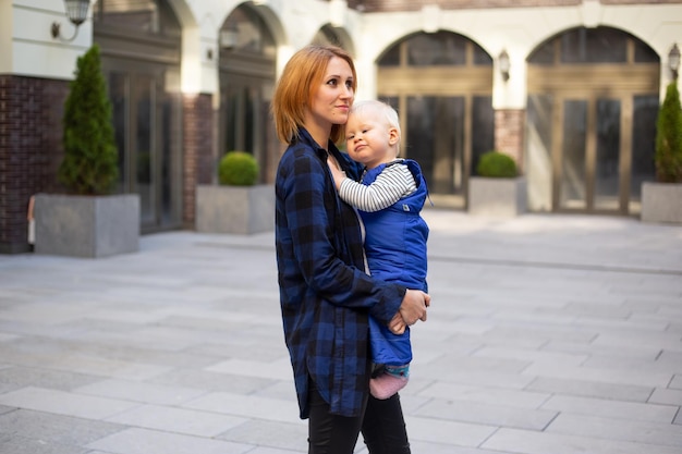 Madre con niño bebé en ropa elegante al aire libre en el fondo urbano