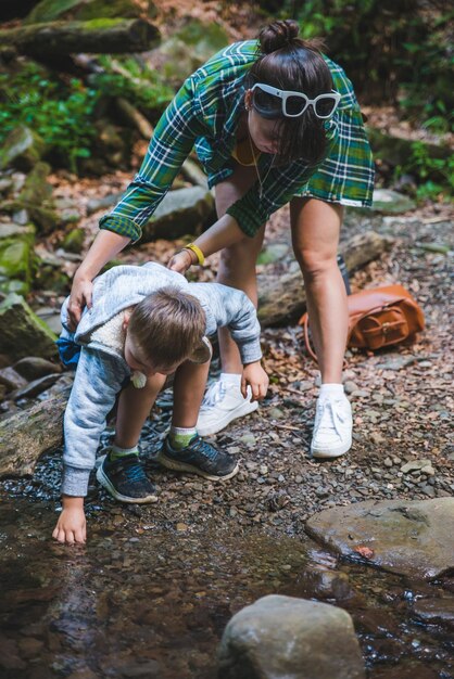 Madre con niño cerca del concepto de cuidado del río de las montañas