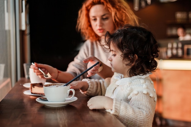 Una madre y un niño comiendo una taza de café en una cafetería.