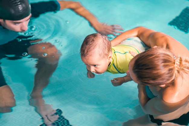 Madre con niño e instructor de natación piscina cubierta