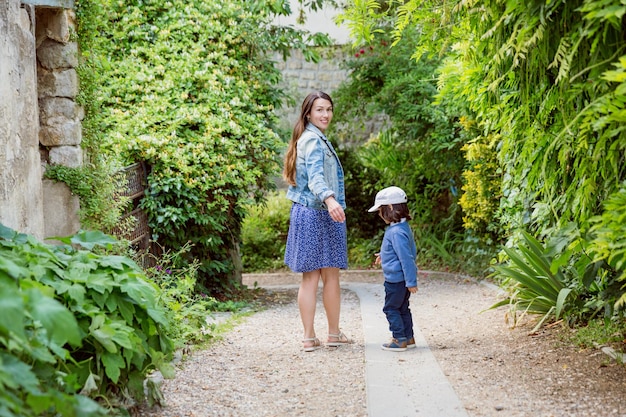 Madre y niño guapo caminando al aire libre en el parque de la ciudad vieja