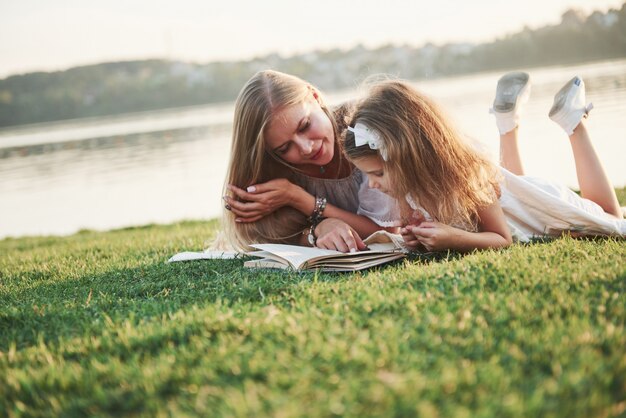 Madre con un niño lee un libro sobre la hierba