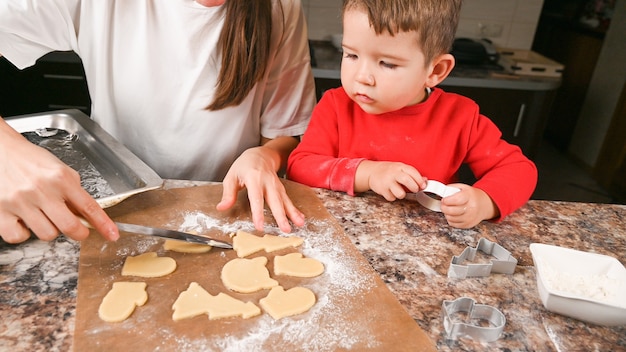 La madre y el niño pequeño hacen galletas de Navidad en la cocina