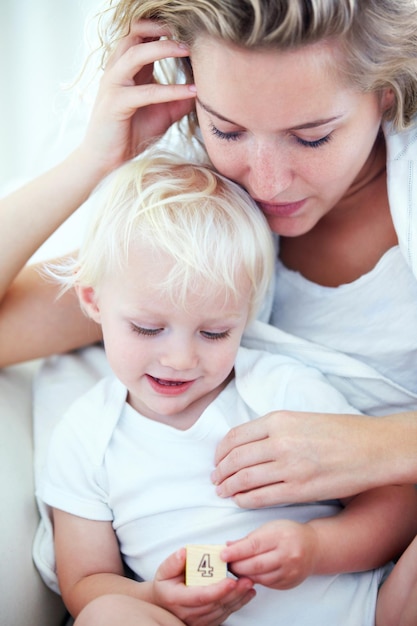 Madre niño pequeño y juntos con amor en el sofá para la unión de aprendizaje y relajarse con la seguridad para el niño madre soltera niño y bloques de juguetes educativos para el desarrollo del crecimiento y feliz en casa en el sofán