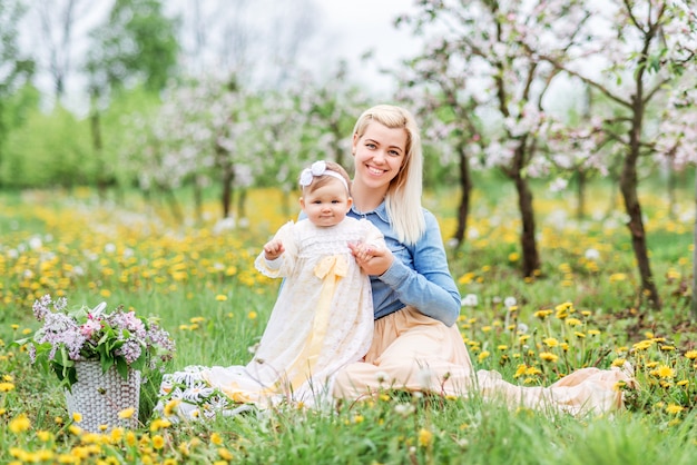 Madre con un niño pequeño en un paseo en un jardín floreciente.