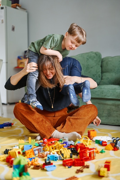 Madre con niños abrazándose, divirtiéndose, riendo en casa. Padre con hijos pasando tiempo juntos