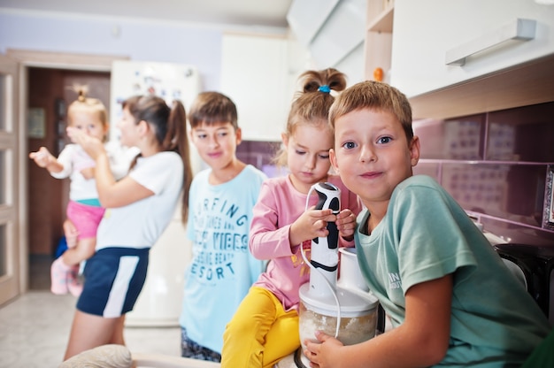 Madre con niños cocinando en la cocina, momentos infantiles felices.