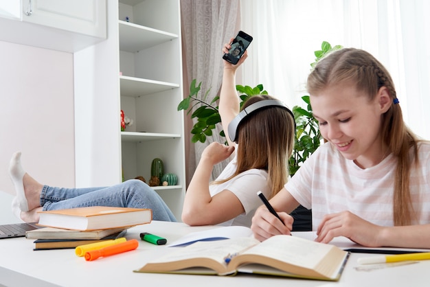 La madre no está ayudando a la hija a hacer la tarea mientras usa su teléfono inteligente y escucha música con auriculares