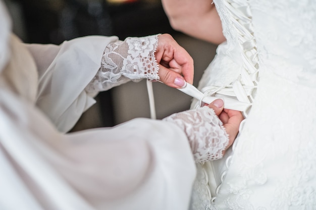 Madre de la novia ayuda a atar el vestido de novia.