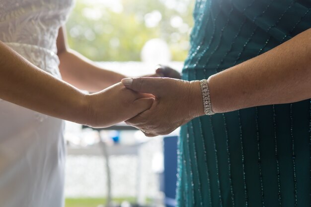 Madre de la novia dando las manos a la novia en la mañana antes de la ceremonia, fotos en la celebración de la boda.