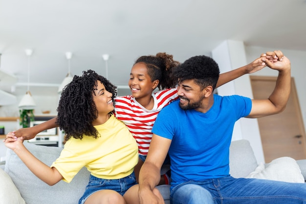 Madre y padre africanos alegres jugando con su hija en casa