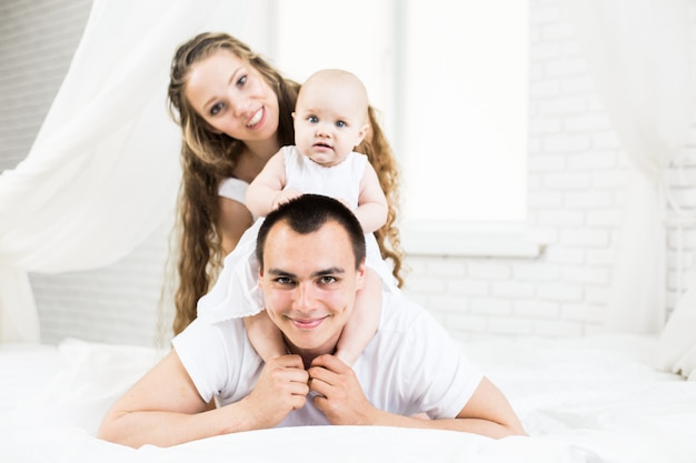 Madre y padre con bebé en una cama.