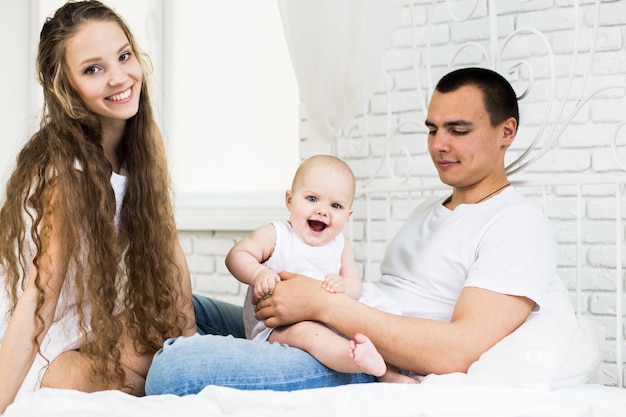 Madre y padre con bebé en una cama.