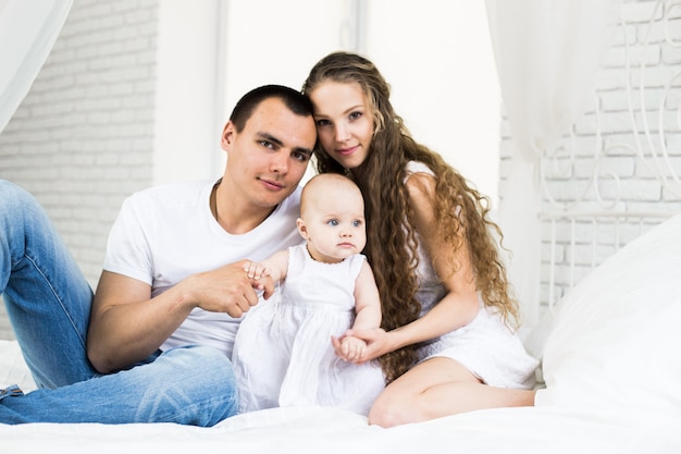 Madre y padre con bebé en una cama