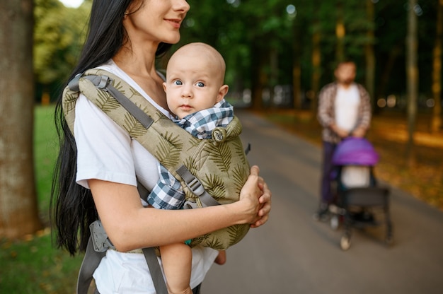 Madre, padre y bebé caminando por el callejón en el parque de verano