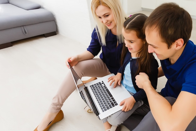 madre, padre e hija estudiando en la computadora portátil. Distanciamiento social y autoaislamiento en el encierro por cuarentena
