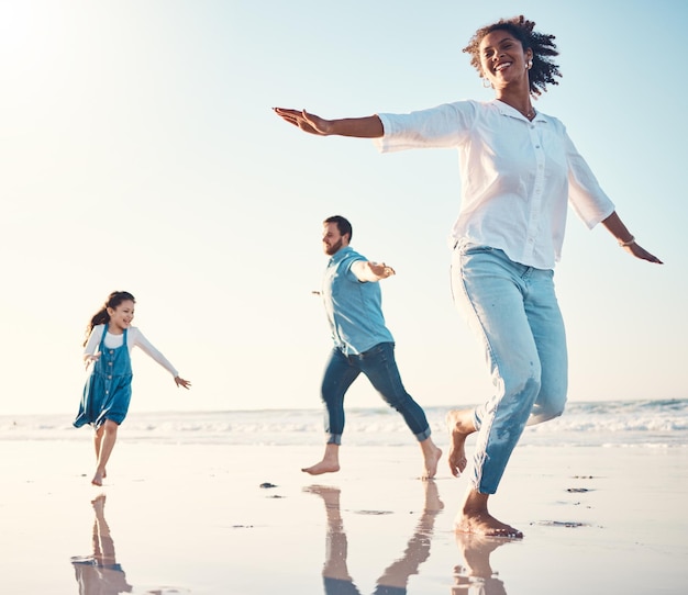 Madre, padre e hija en la playa para bailar juntos mientras están al aire libre para viajar o vacacionar en verano Familia o niños al atardecer y una niña divirtiéndose con sus padres en la costa junto al océano