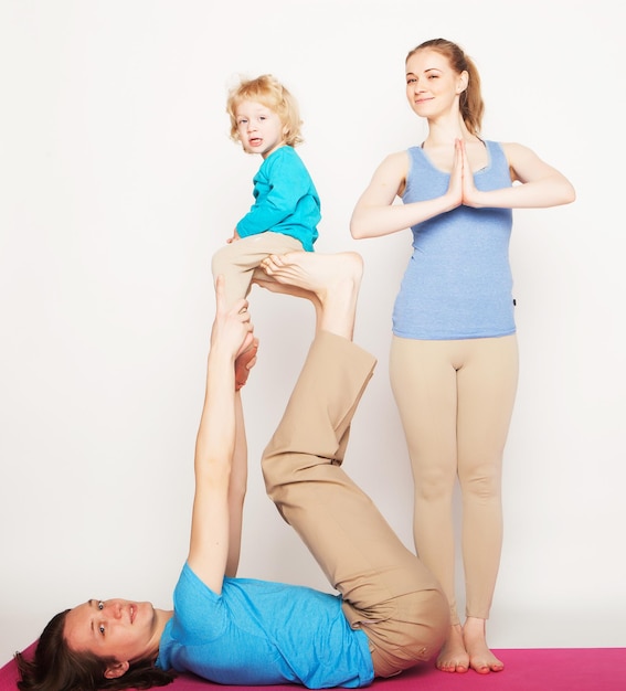 Madre, padre e hijo haciendo yoga sobre fondo blanco.
