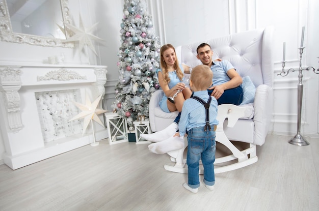 Madre, padre e hijo juegan contra el fondo de un árbol de Navidad