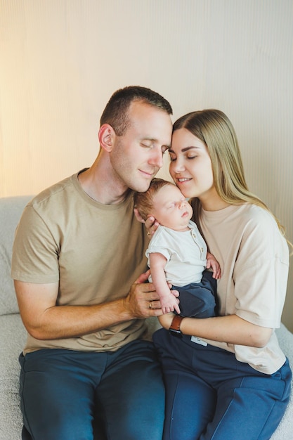 Madre y padre felices abrazando a su recién nacido Padres y un niño sonriente en sus brazos Una joven familia con un recién nacido