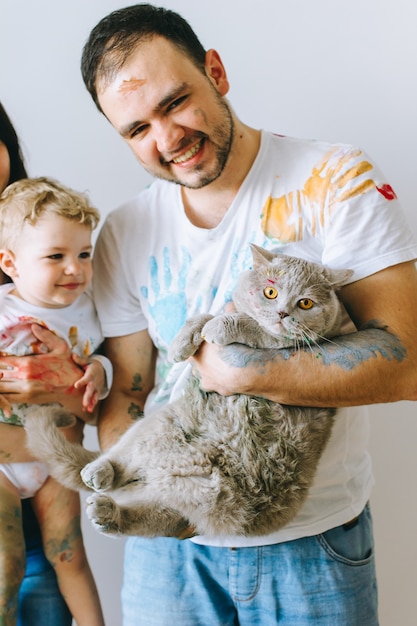 Foto madre padre hijo y gato sobre un fondo blanco después de jugar pintura