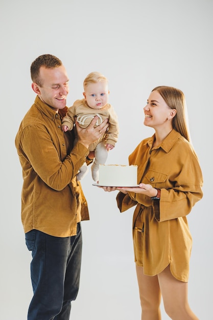 Madre y padre jóvenes felices sosteniendo a su hijo recién nacido en sus brazos y dándole un pastel Padres celebrando su cumpleaños con su hijo pequeño El concepto de vacaciones familiares