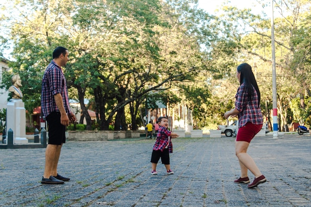 Madre y padre jugando con su hijo feliz en la plaza.