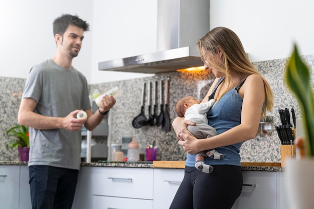 Madre y padre preparando un biberón para su recién nacido en la cocina