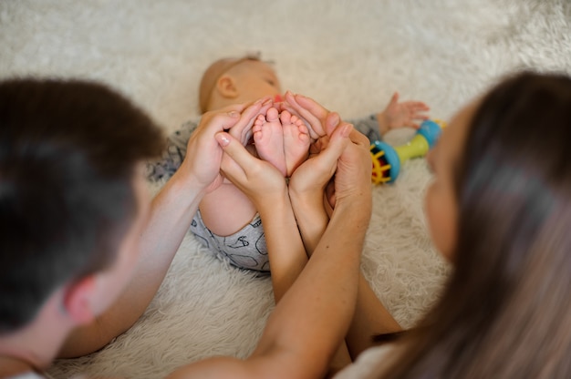 Madre y padre sosteniendo en sus manos hija pies