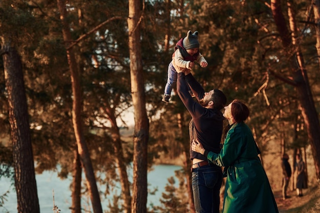 Madre y padre con su hijo pequeño dan un paseo por el bosque de primavera durante el día