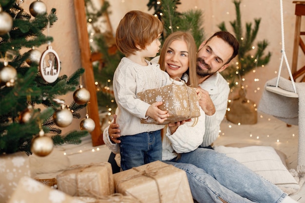 Madre padre y su hijo sentados cerca del árbol de Navidad en casa