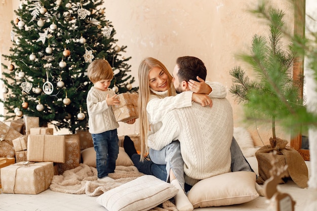 Madre padre y su hijo sentados cerca del árbol de Navidad en casa