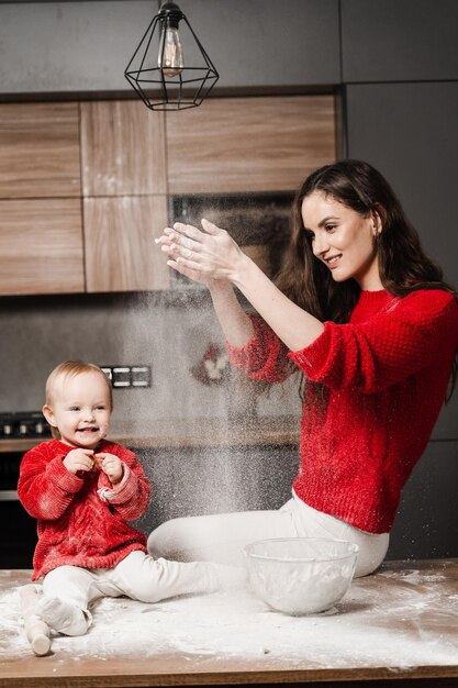 La madre y la pequeña ayudante están preparando galletas y tirando harina en la cocina en casa Familia feliz y amorosa está cocinando comida de panadería casera y jugando juntos