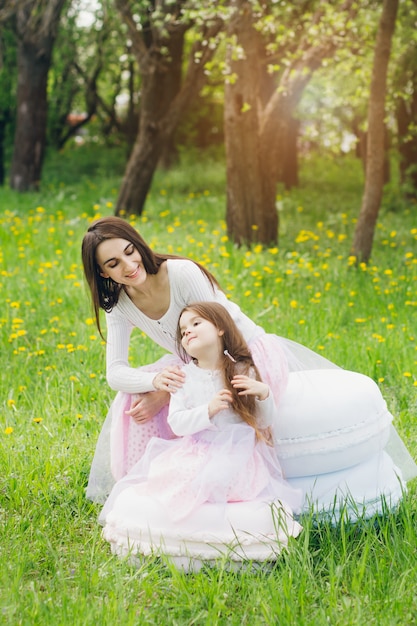 Madre y una pequeña hija caminan en la primavera Apple floreciente