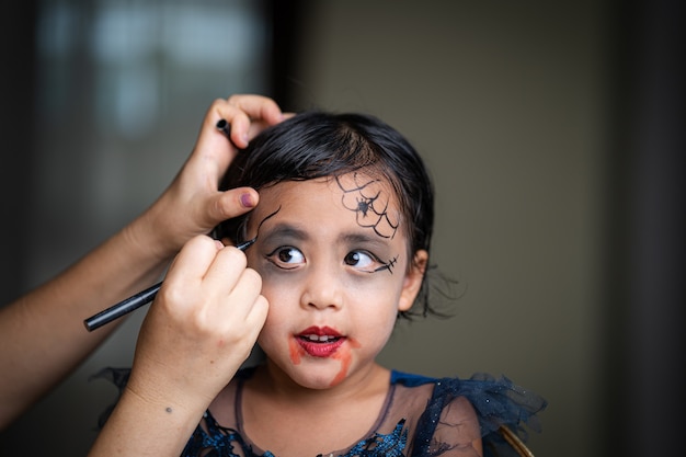 Madre pintando cara de hijas fiesta de Halloween