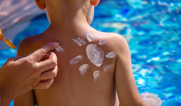 La madre pone crema en la espalda de su hijo Cuidando la piel del bebé Protectores solares en el enfoque selectivo de viaje