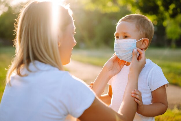 La madre se pone la máscara médica estéril del niño en el parque Covid2019