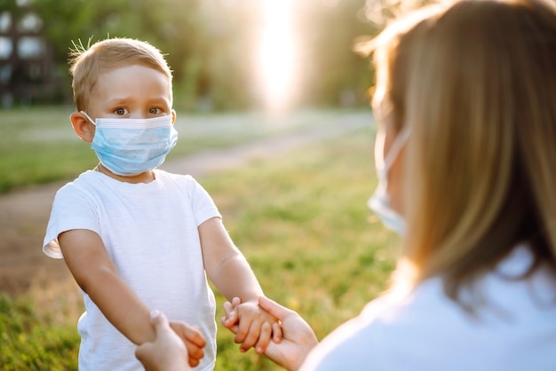 La madre se pone la máscara médica estéril del niño en el parque Covid2019