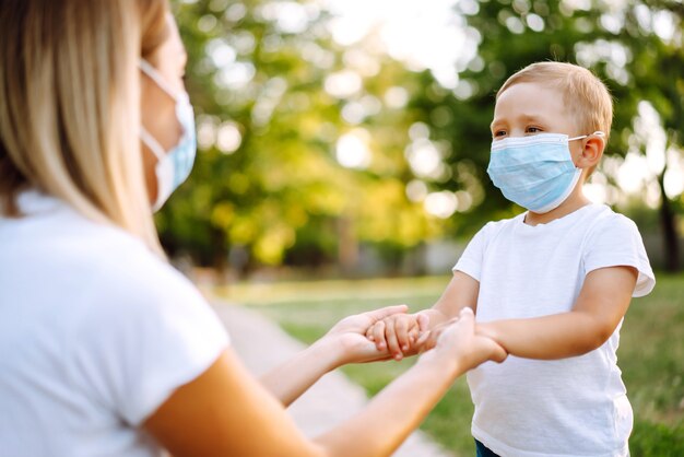 La madre se pone la máscara médica estéril del niño en el parque Covid2019