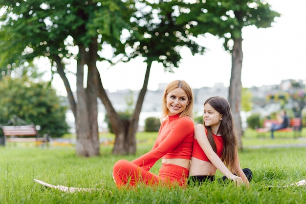 Madre practicando yoga con su hija al aire libre