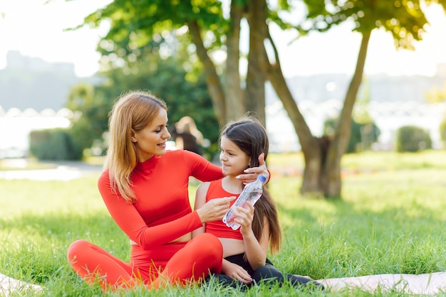 Madre practicando yoga con su hija al aire libre