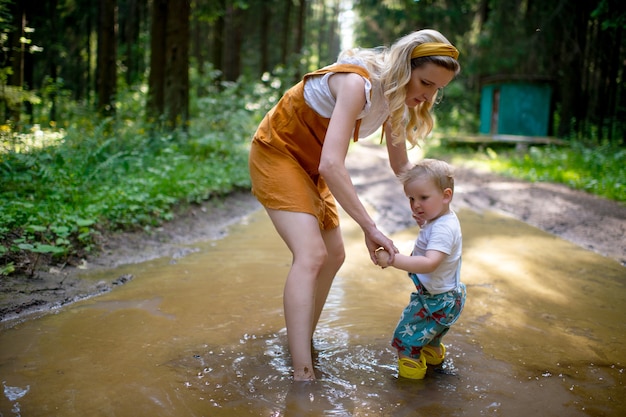 Madre preocupada posando con su hijo en el charco en el bosque